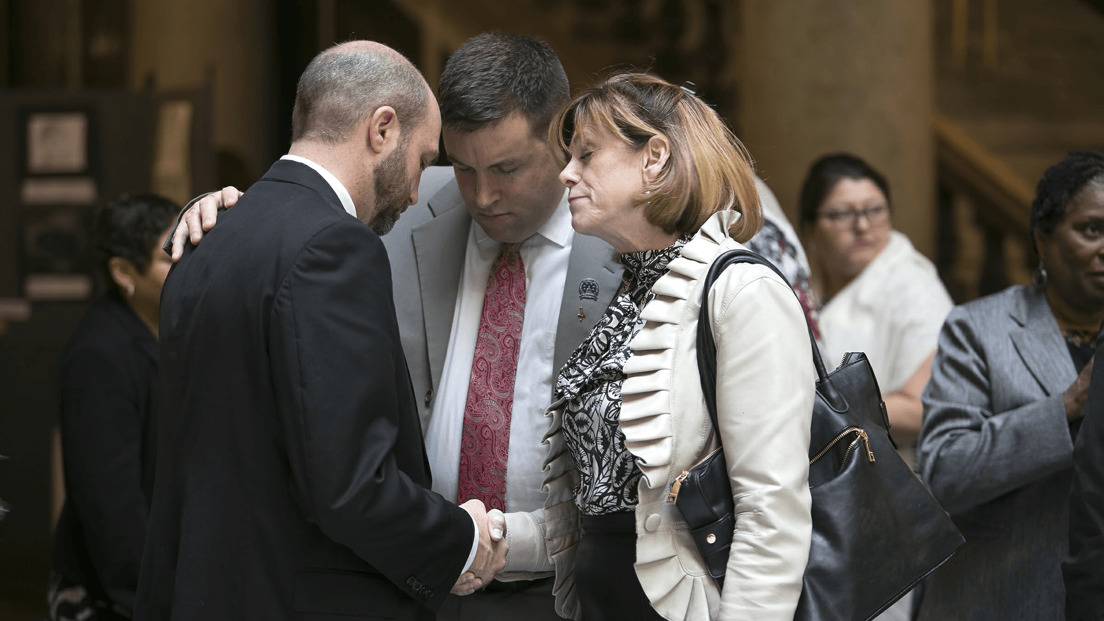 Chaplain Matthew Barnes praying with legislators