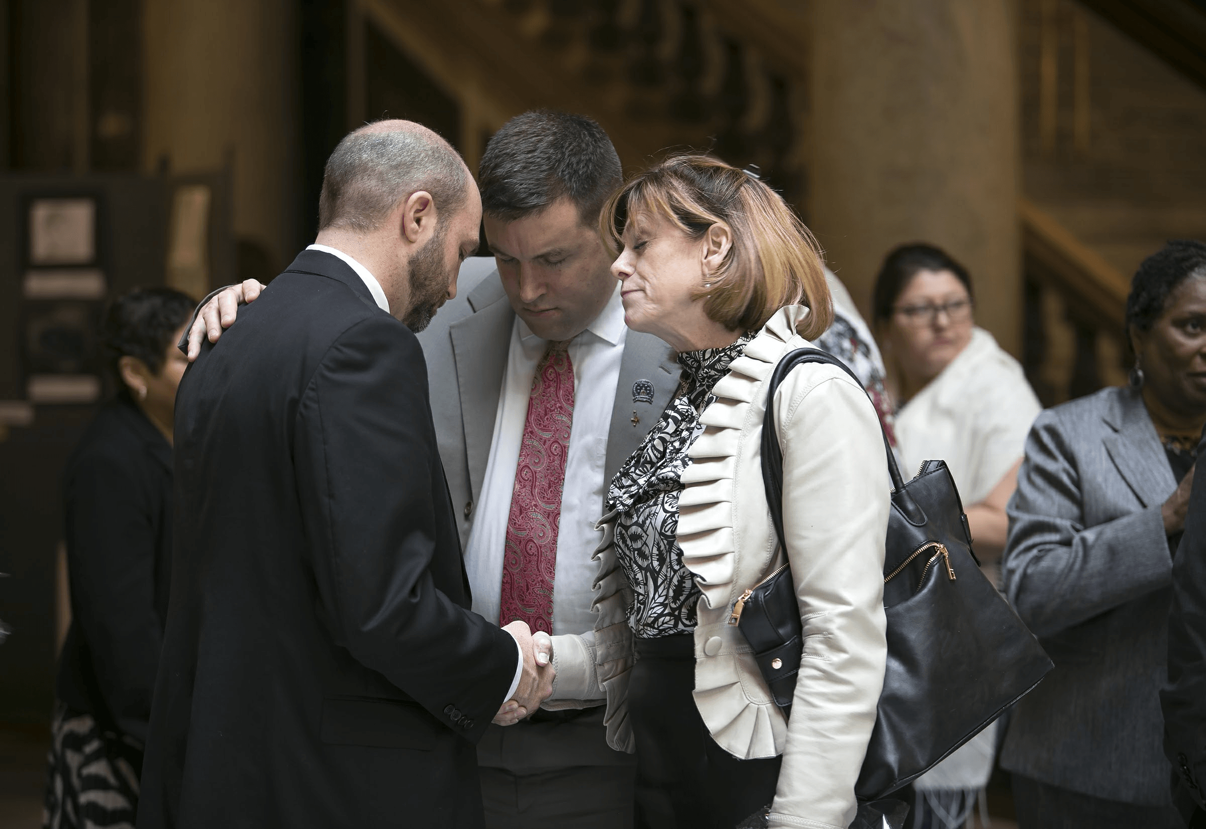Chaplain Matthew Barnes praying with legislators