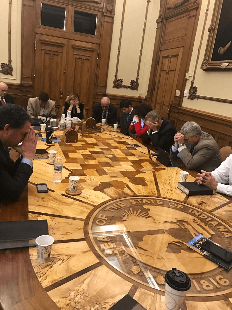 A picture of legislators praying during a legislators Bible study in the governors office